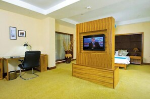Una habitación de hotel con televisión, escritorio, silla, cama y mesita de noche.