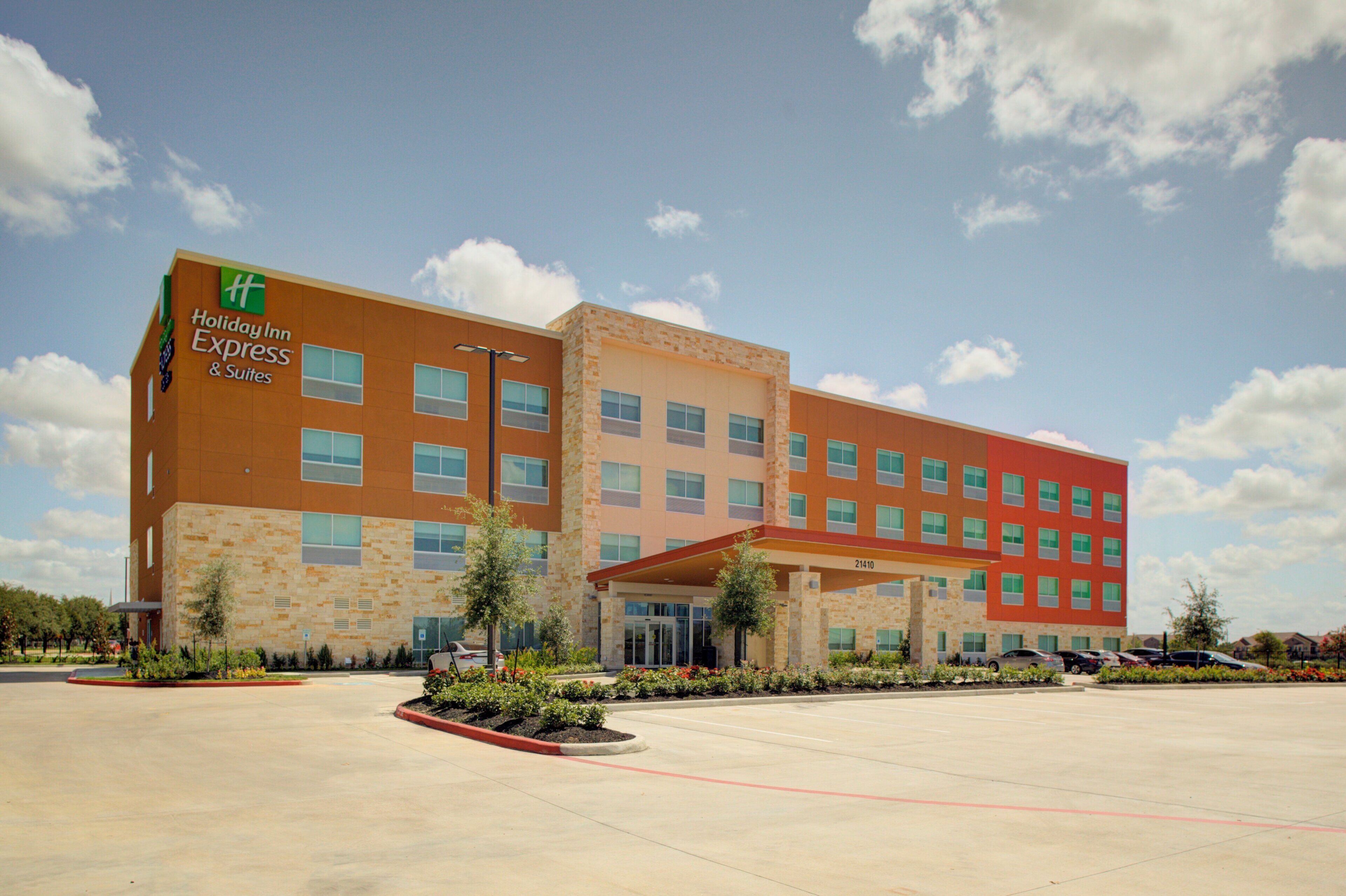 A Holiday Inn Express building with a modern design, featuring a mix of brick and glass facade, and a parking lot in front.
