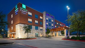 Un edificio Holiday Inn Express con fachada de piedra, varias ventanas y una zona de entrada cubierta.