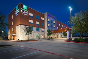 A Holiday Inn Express building with a stone facade, multiple windows, and a covered entrance area. - Holiday Inn Express & Suites Houston NW - Cypress Grand Pky by IHG (Cypress)
