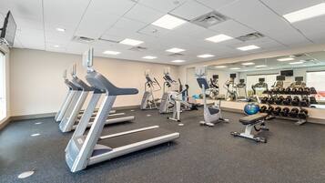 A gym with treadmills, elliptical machines, and free weights.