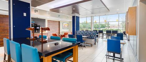 A modern dining area with a black bar, blue chairs, and a brick accent wall.