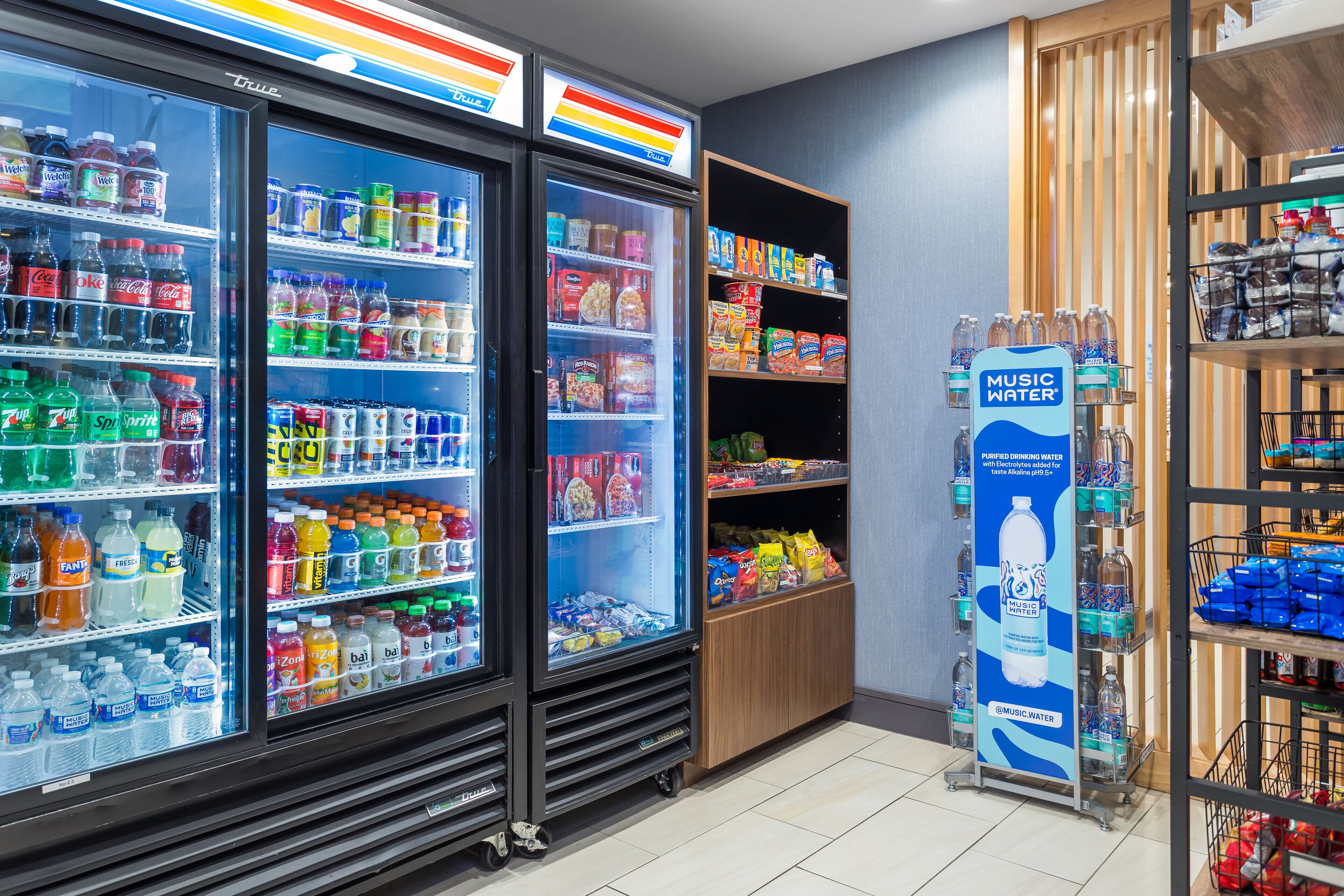 A beverage cooler stocked with various drinks and a display of snacks and bottled water.