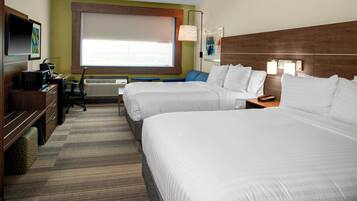A hotel room with two beds, a desk with a computer, a chair, an air conditioning unit, and a television on the wall.