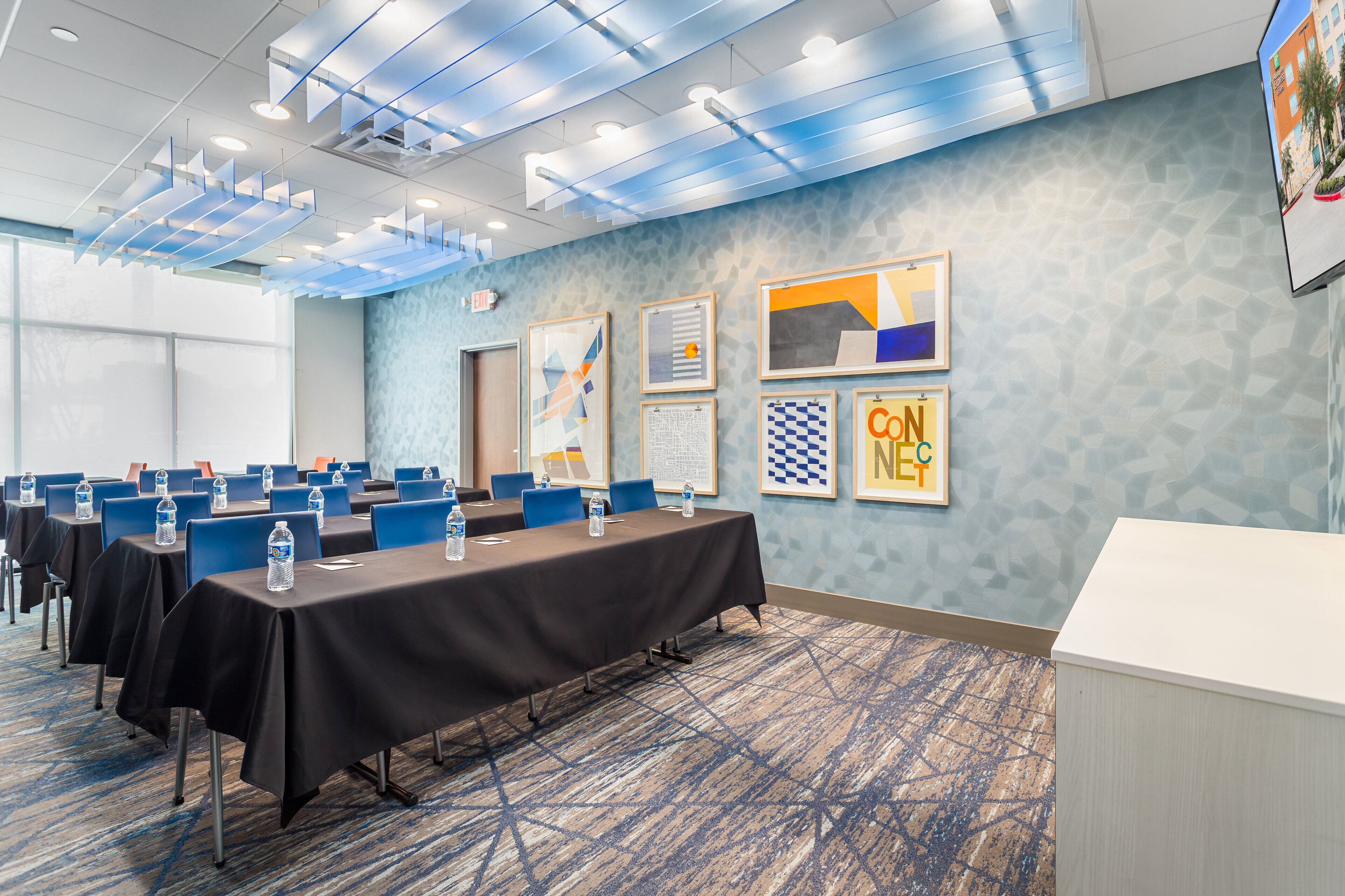 Un salón de conferencias con mesas, sillas y un mostrador de recepción blanco.