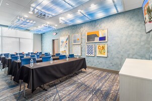Un salón de conferencias con mesas, sillas y un mostrador de recepción blanco.