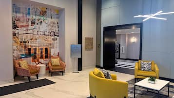 A lobby with a cityscape mural, two yellow armchairs, a coffee table, and a sign indicating registration on level 4.