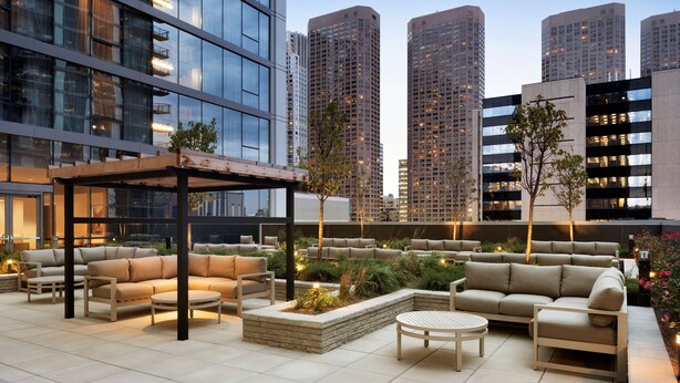 A rooftop patio with outdoor seating, a pergola, and a view of tall buildings. - Hampton Inn Chicago West Loop Fulton Market Area (Chicago)