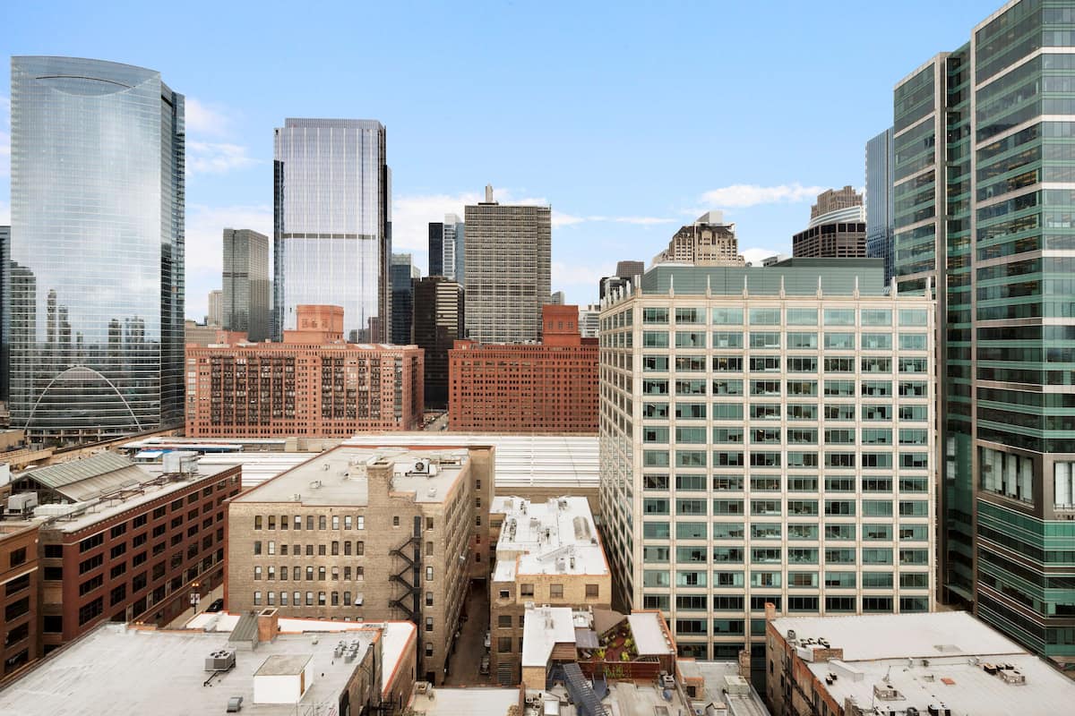 A cityscape with various high-rise buildings, including a mix of modern glass structures and older brick buildings.