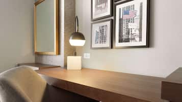A modern desk with a lamp, a chair, and framed pictures on the wall.