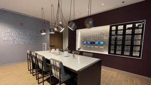 Un comedor moderno con una isla central, sillas, luces colgantes y una pared decorativa con una cita inspiradora.