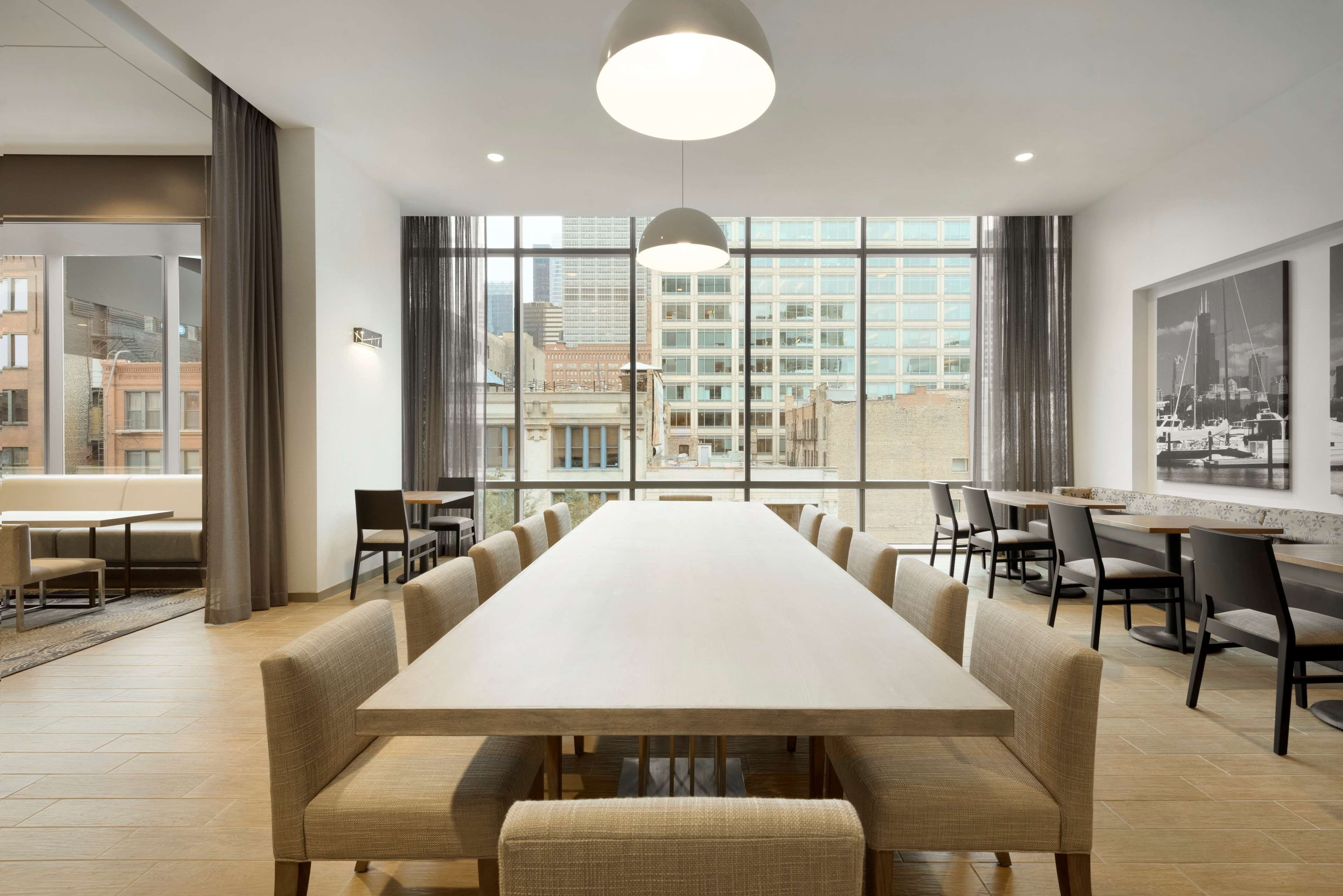A conference room with a long table, chairs, and a city view through large windows.