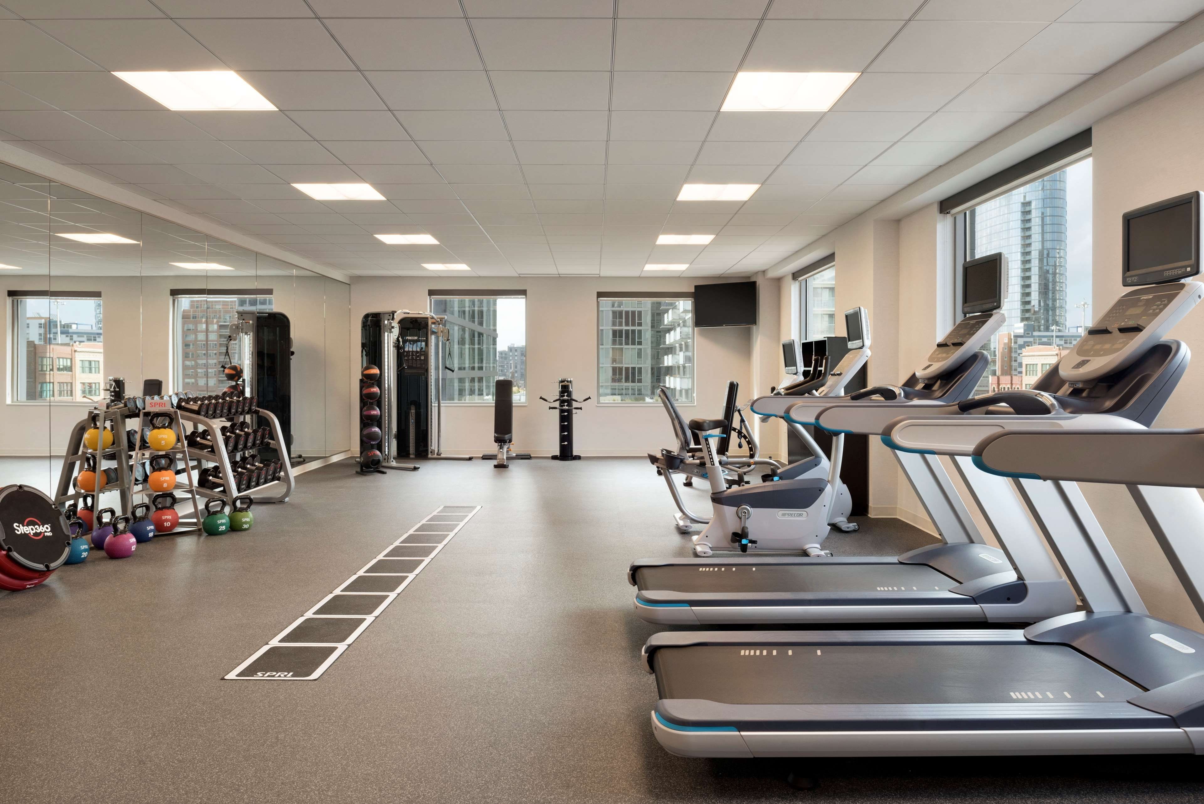 A gym with treadmills, weight machines, and kettlebells.