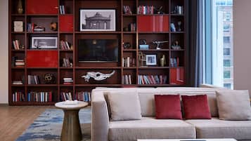 Een woonkamer met een bank, salontafel en een boekenkast vol boeken en decoratieve objecten.