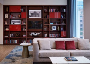 Una sala de estar con sofá, mesa de centro y una estantería llena de libros y objetos decorativos.