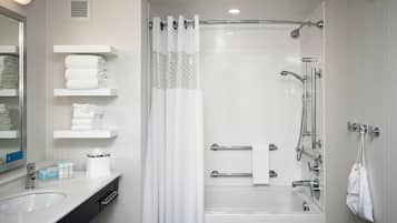 Un baño moderno con bañera, ducha y tocador con espejo y toalleros.