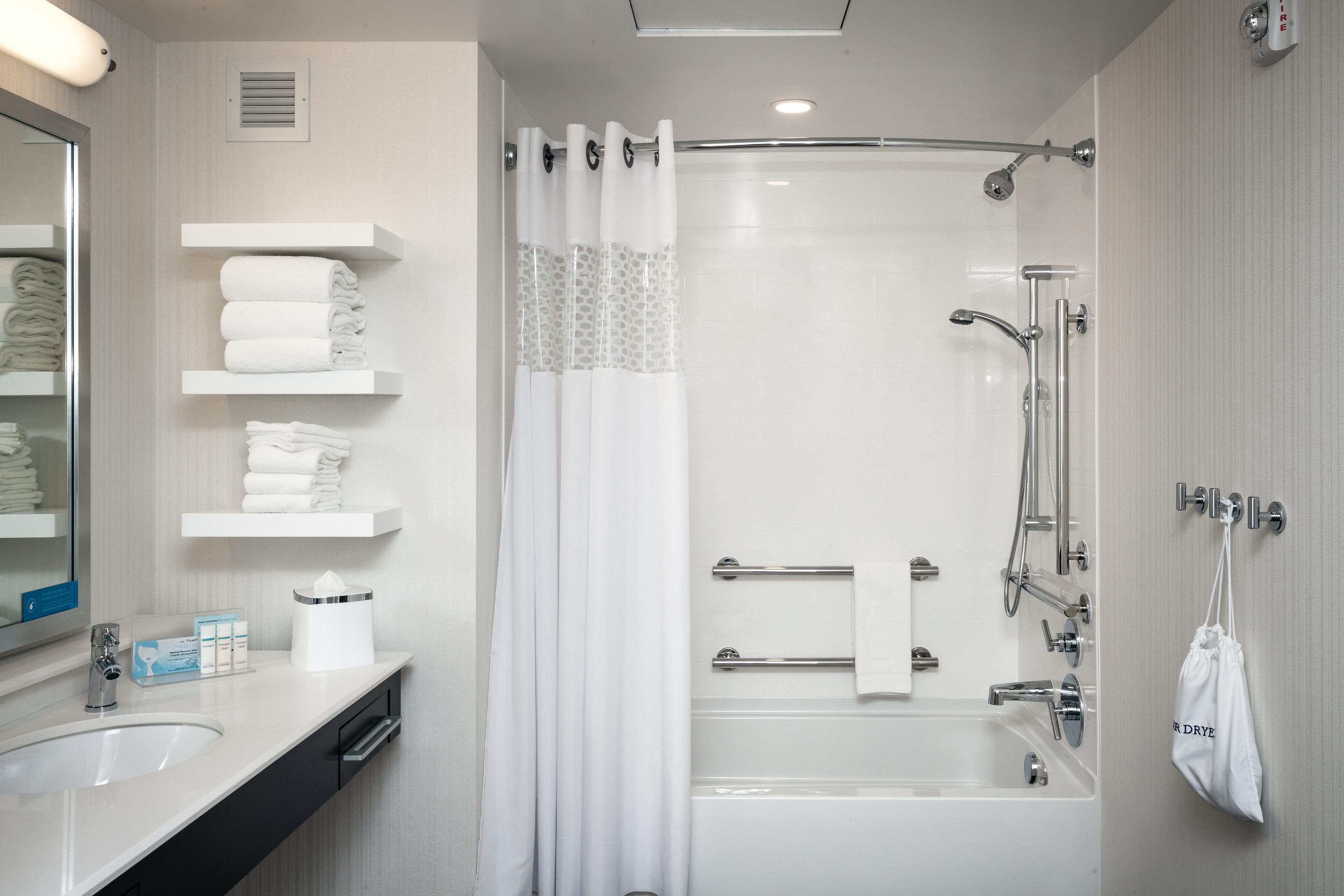 A modern bathroom with a bathtub, shower, and a vanity with a sink and towel rack.