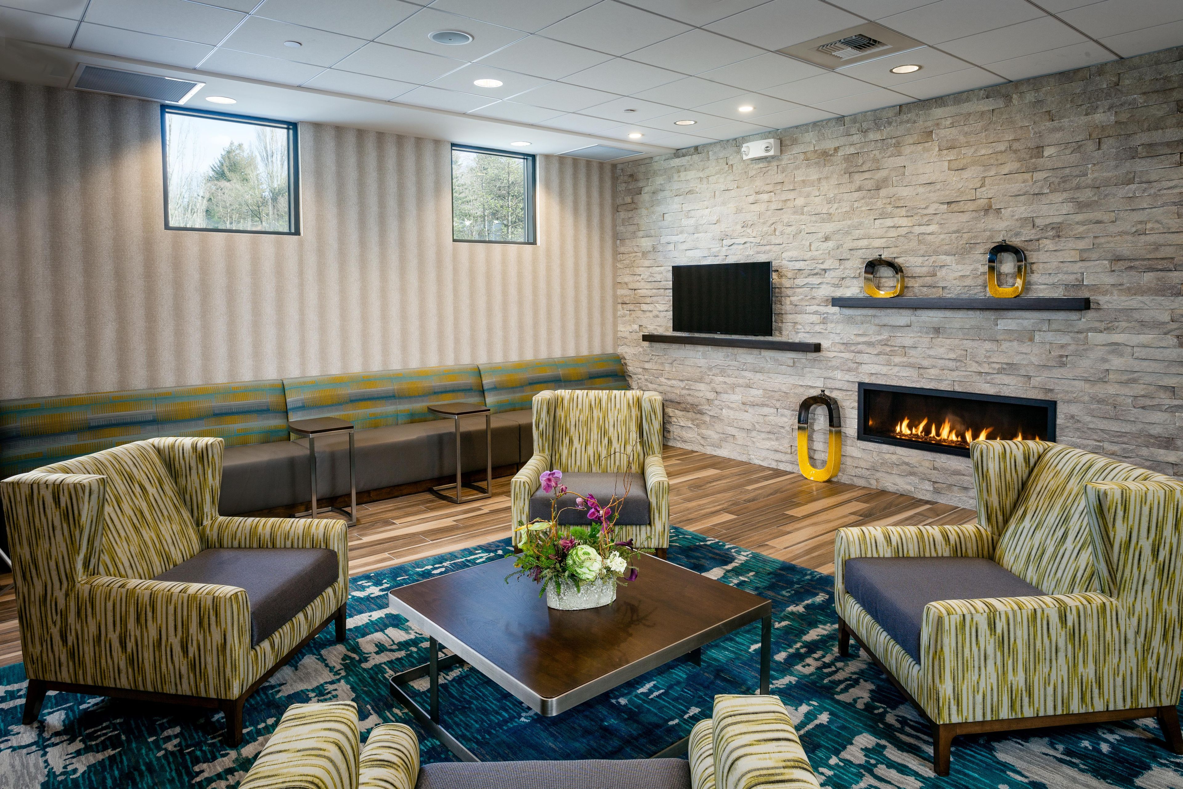 A lounge area with a sofa, armchairs, a coffee table, and a fireplace.