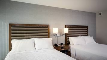 A hotel room with two beds, each with a wooden headboard, a nightstand with a lamp, and a phone.