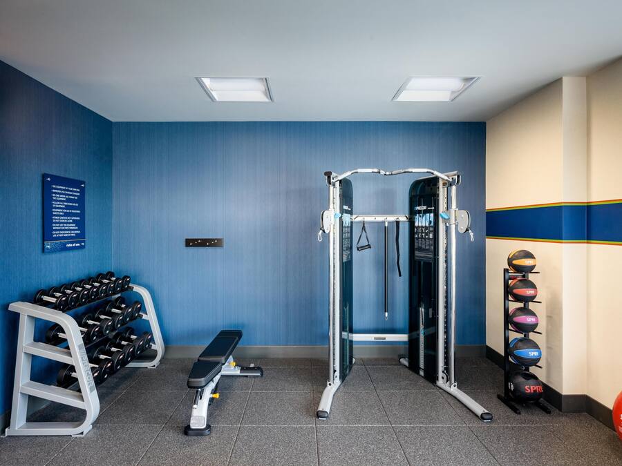 Un gimnasio con barra de dominadas, mancuernas y pelotas de ejercicio.