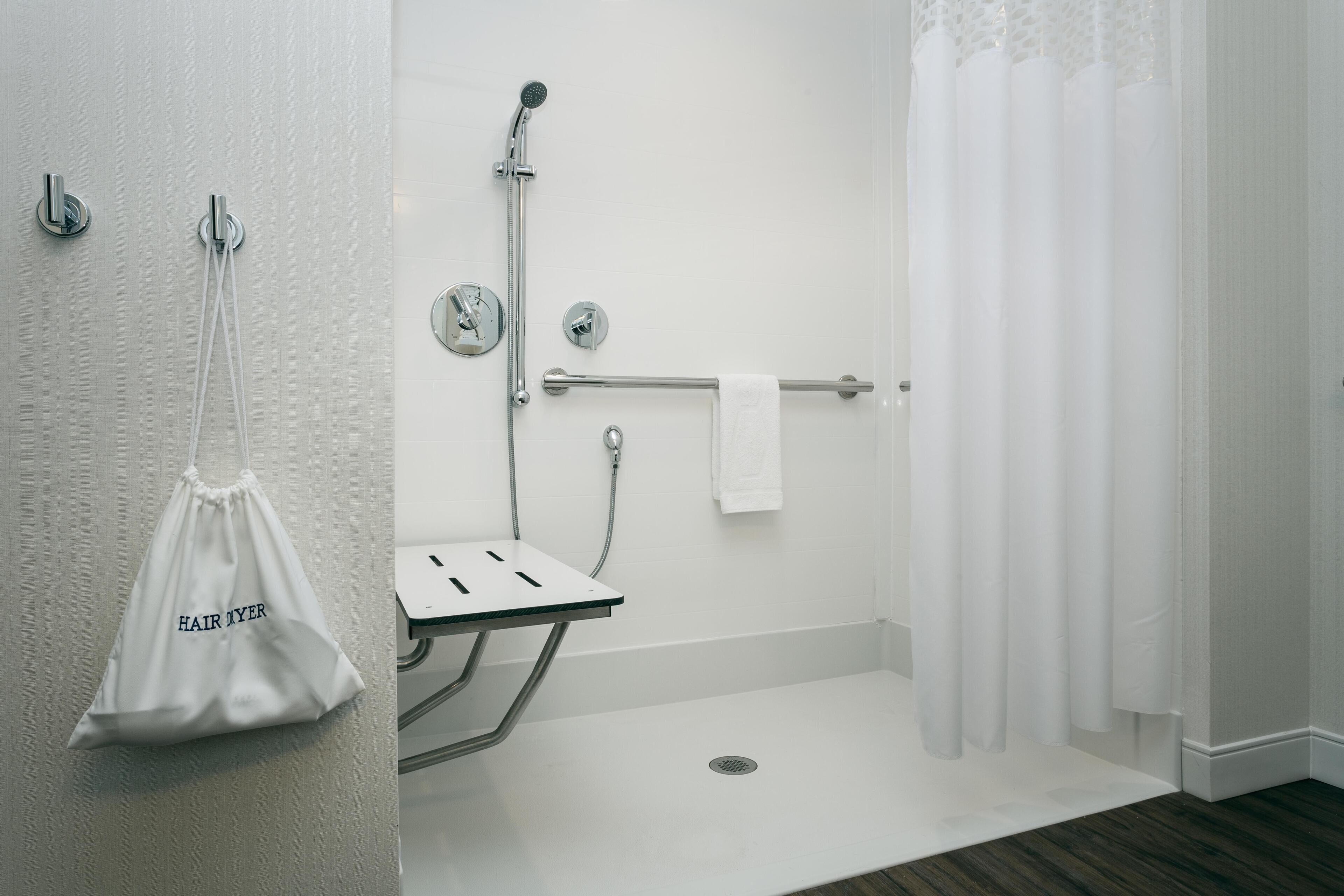 A modern bathroom with a shower, a towel rack, and a small sink.