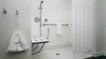 A modern bathroom with a shower, a towel rack, and a small sink.