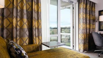 Ein Hotelzimmer mit einem Bett, einem kleinen Tisch, einem Stuhl und Blick ins Freie.