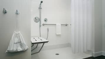 Un baño moderno con ducha, toallero y un lavamanos pequeño.
