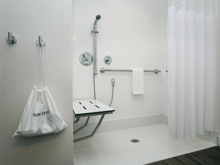 Un baño moderno con ducha, toallero y un lavamanos pequeño.