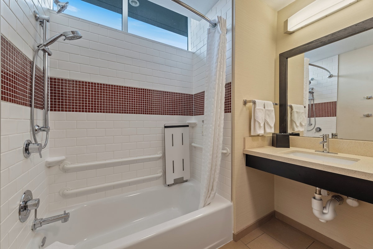 A modern bathroom with a bathtub, shower, and sink.