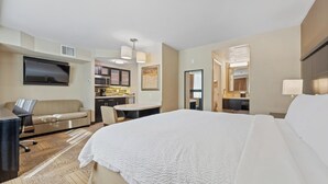 A hotel room with a bed, a desk, a sofa, a TV, and a kitchenette. - Staybridge Suites Denver Downtown by IHG (Denver)