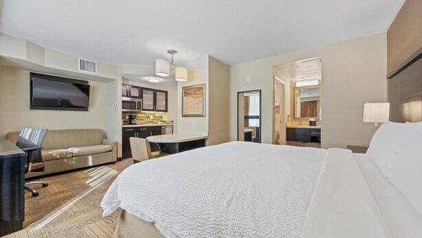 A hotel room with a bed, a desk, a sofa, a TV, and a kitchenette. - Staybridge Suites Denver Downtown by IHG (Denver)