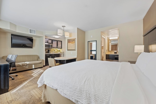 A hotel room with a bed, a desk, a sofa, a TV, and a kitchenette. - Staybridge Suites Denver Downtown by IHG (Denver)
