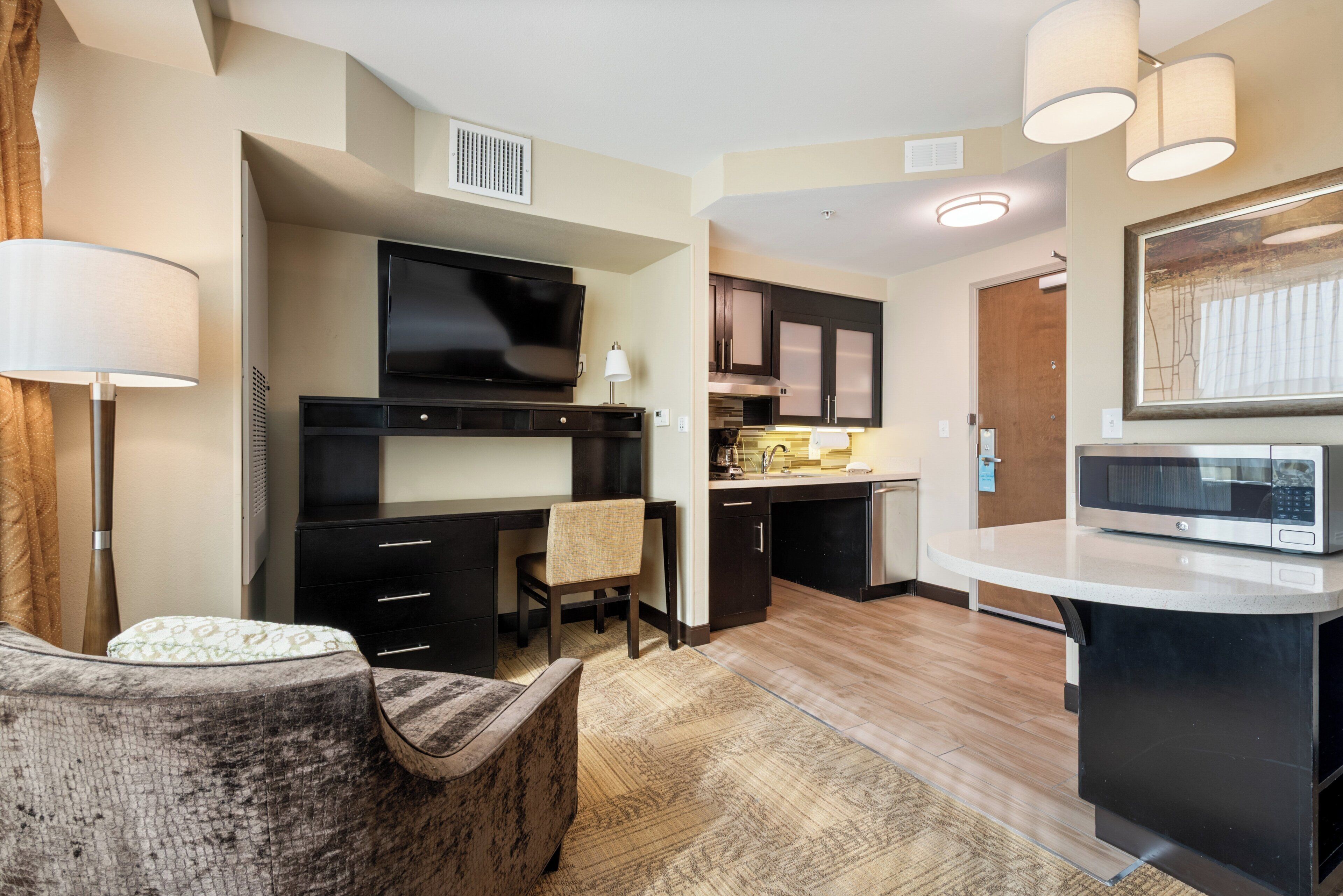 Un espacio habitable compacto con kitchenette, televisor de pantalla plana, zona de comedor y sofá.