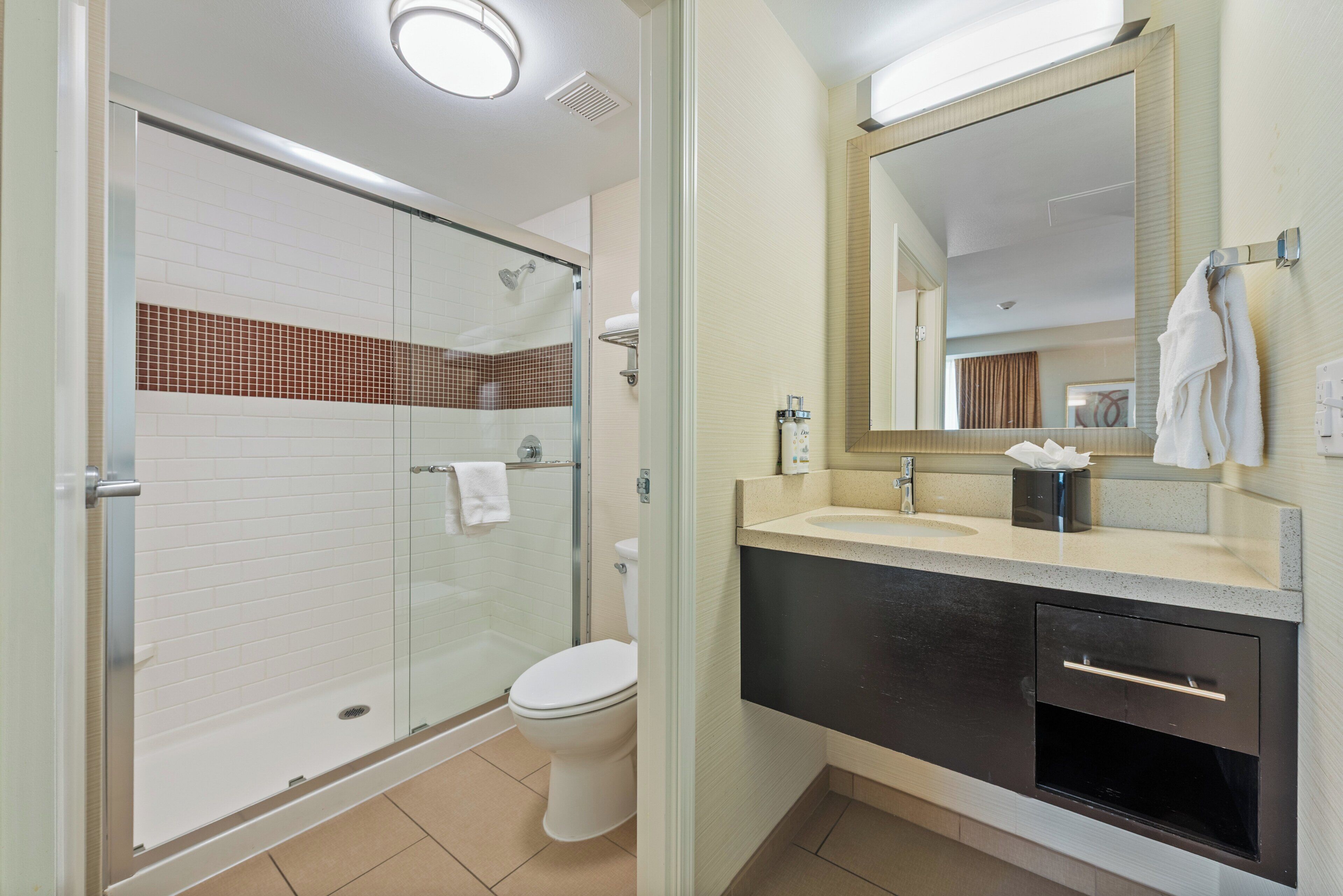 A modern bathroom with a glass-enclosed shower, a toilet, a sink with a mirror, and a towel rack.