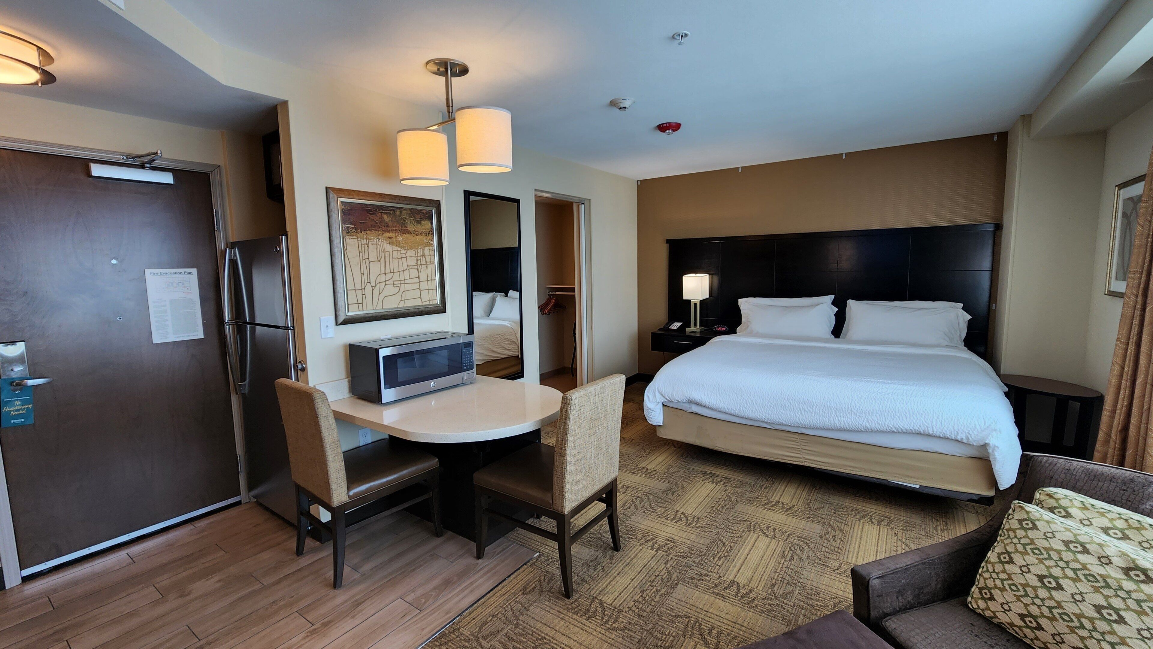 Une chambre d’hôtel équipée d’un lit, d’un bureau, d’un four à micro-ondes, d’un réfrigérateur et d’un coin repas.