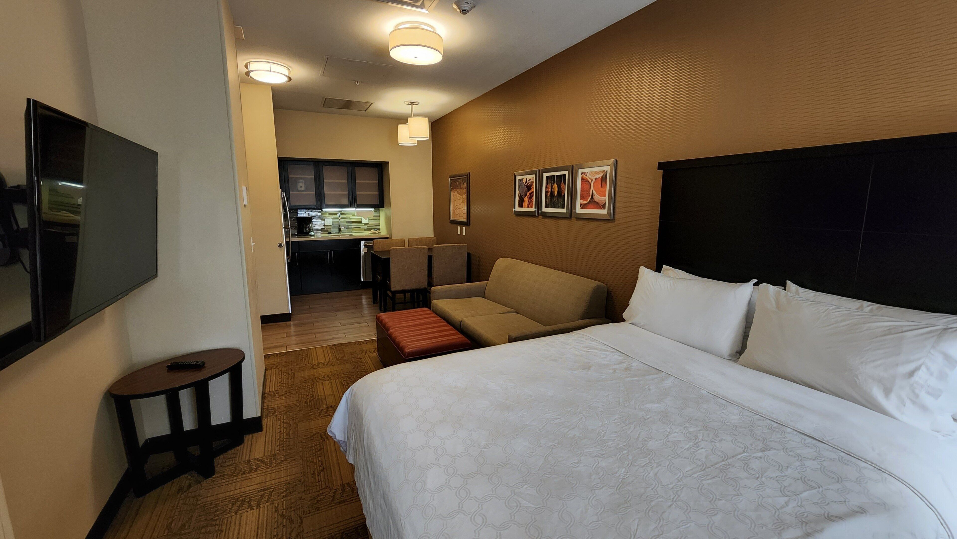 Una camera d'albergo con un letto grande, una TV a parete, angolo cottura e zona pranzo.
