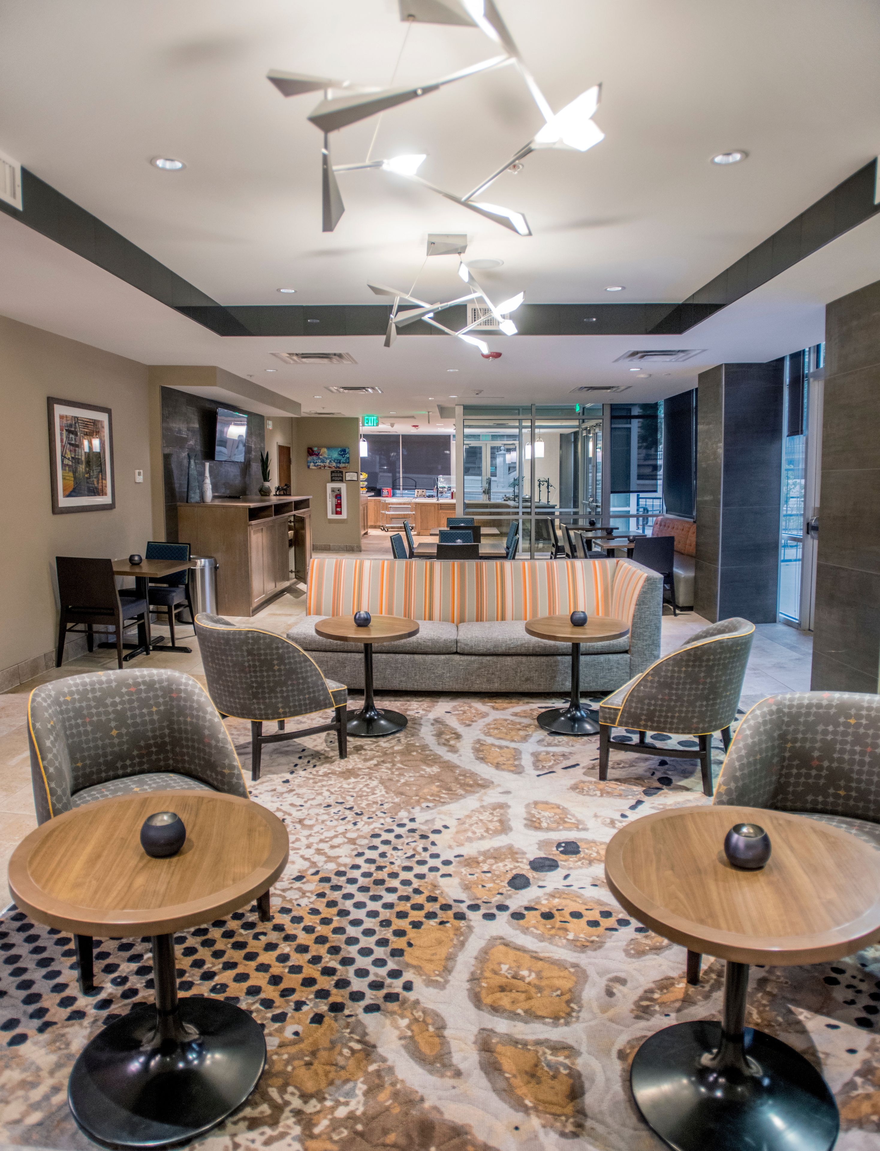 A modern hotel lobby with a seating area, a reception desk, and a patterned floor.
