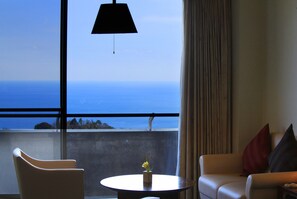 Enjoy ocean views from the large window in this stylish room, featuring a round table and two armchairs.
