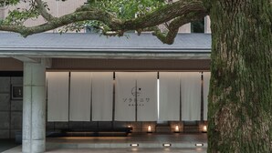A building with a covered entrance, a tree in the foreground, and a sign with Japanese characters. - Soratoniwa Atami Izusan (Atami)