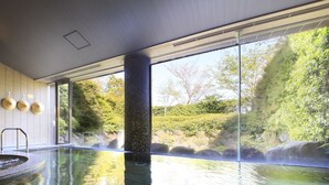 A serene indoor pool with clear glass walls, a stone floor, and a view of a natural landscape. - Soratoniwa Atami Izusan (Atami)