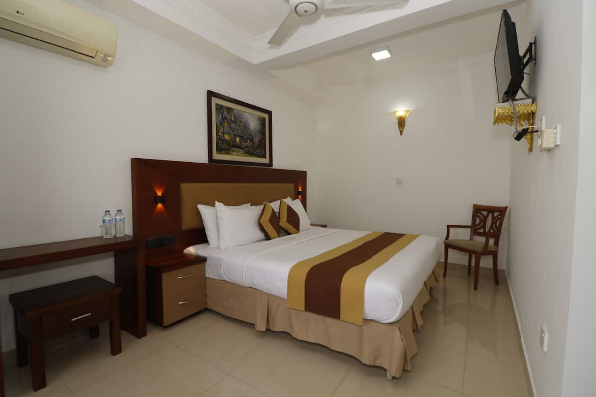 A hotel room with a large bed, a desk, a chair, and a painting on the wall.
