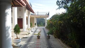 A building with a covered walkway, potted plants, and a view of the surrounding greenery.
