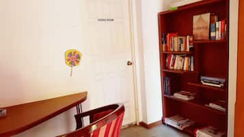 Un coin repas avec une porte blanche portant l’inscription « SALLE À MANGER », une bibliothèque en bois remplie de livres et une chaise à rayures.