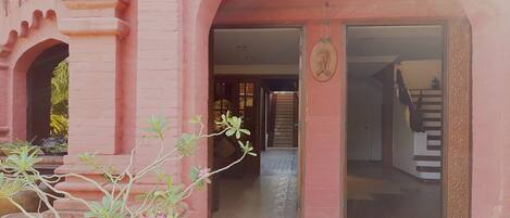 A pink building with a staircase leading to a door.