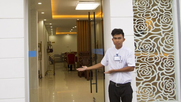 A hotel entrance with a sign reading "Sunny Hotel" and a person standing on the steps. - Hotel Sunny Mandalay (Mandalay)