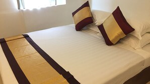 A neatly made bed with a gold and dark brown bedspread, two pillows with a maroon and beige pattern, and a window with natural light. - Hotel Sunny Mandalay (Mandalay)