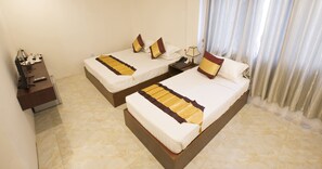 A hotel room with two single beds, a nightstand with a lamp, a telephone, and a small table with a decorative item.
