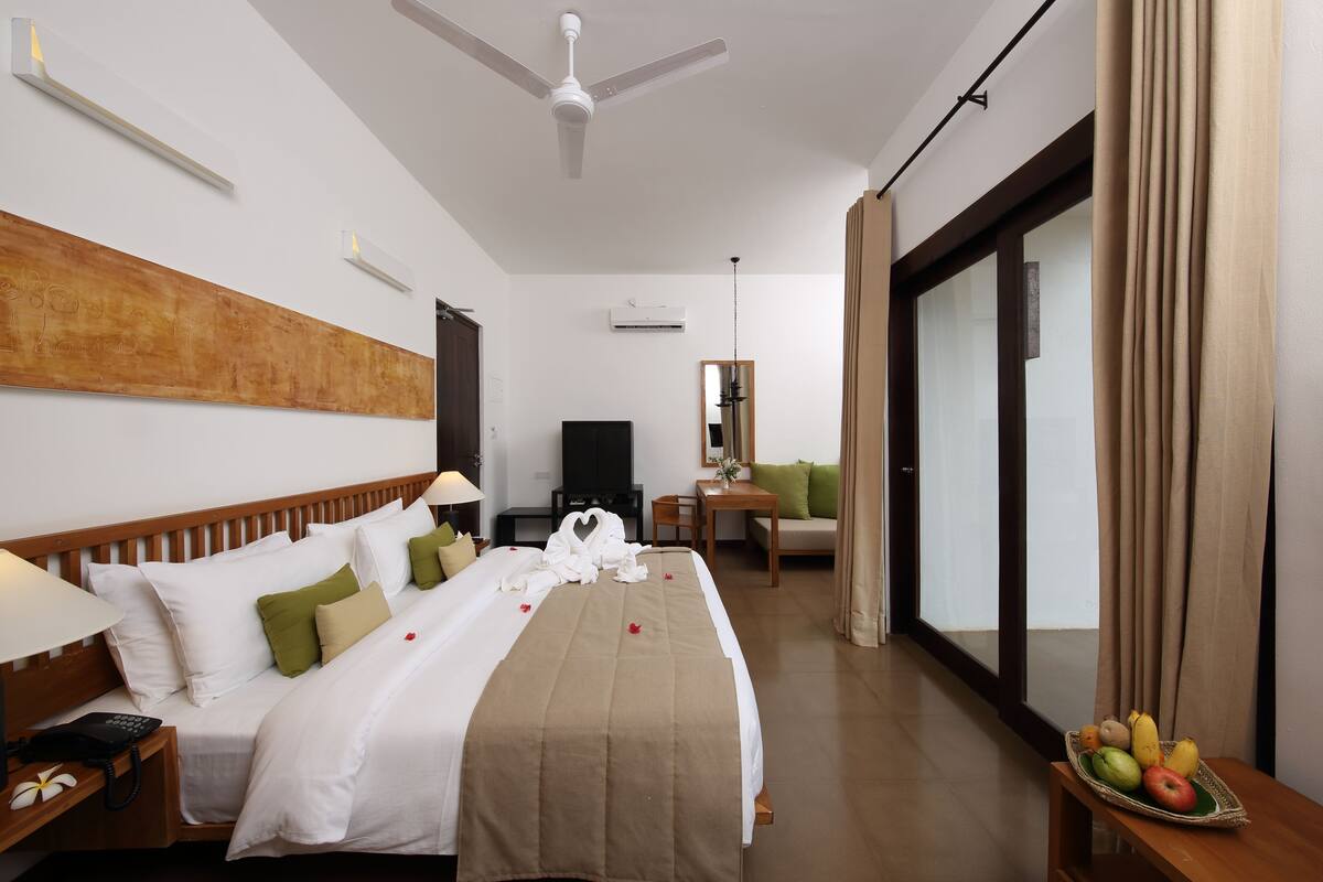 A hotel room with a bed, bedside table, lamp, and a fruit basket.