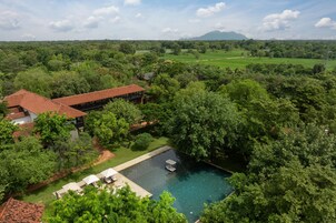 Una casa grande con piscina rodeada de exuberante vegetación y vista a una montaña distante.